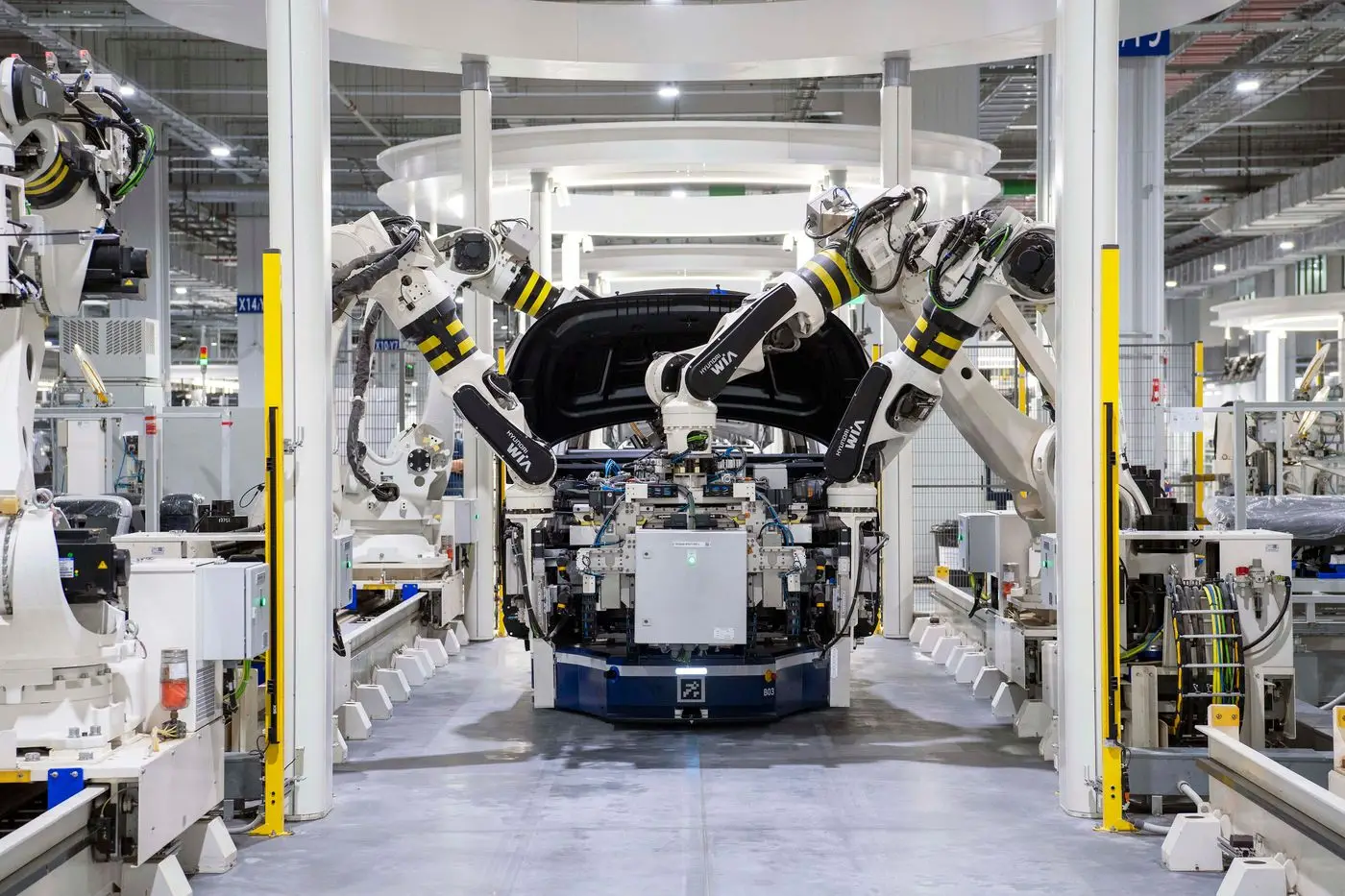 Robotic arms fitting a car body on an automated assembly line