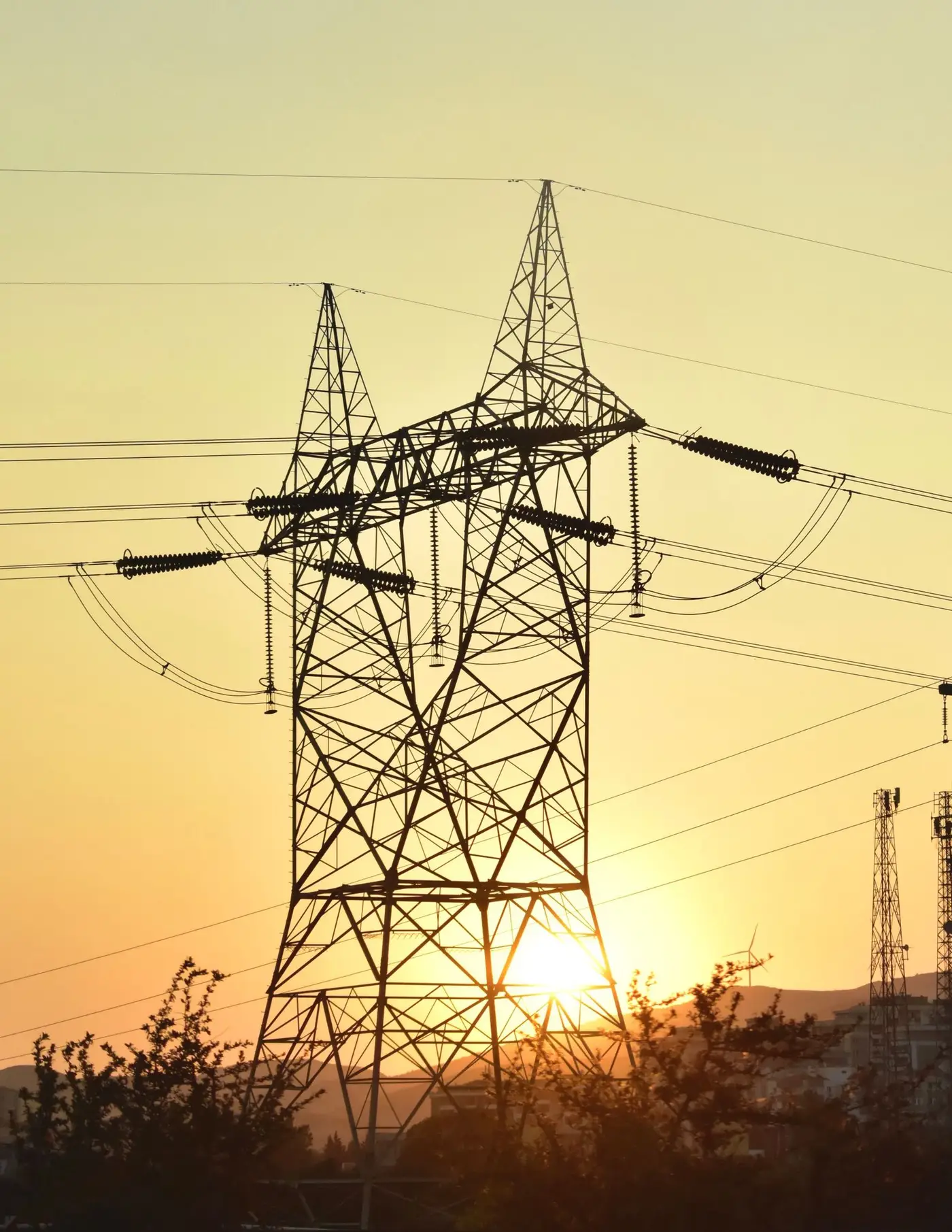 Electricity pylon and transmission lines silhouetted against a sunset