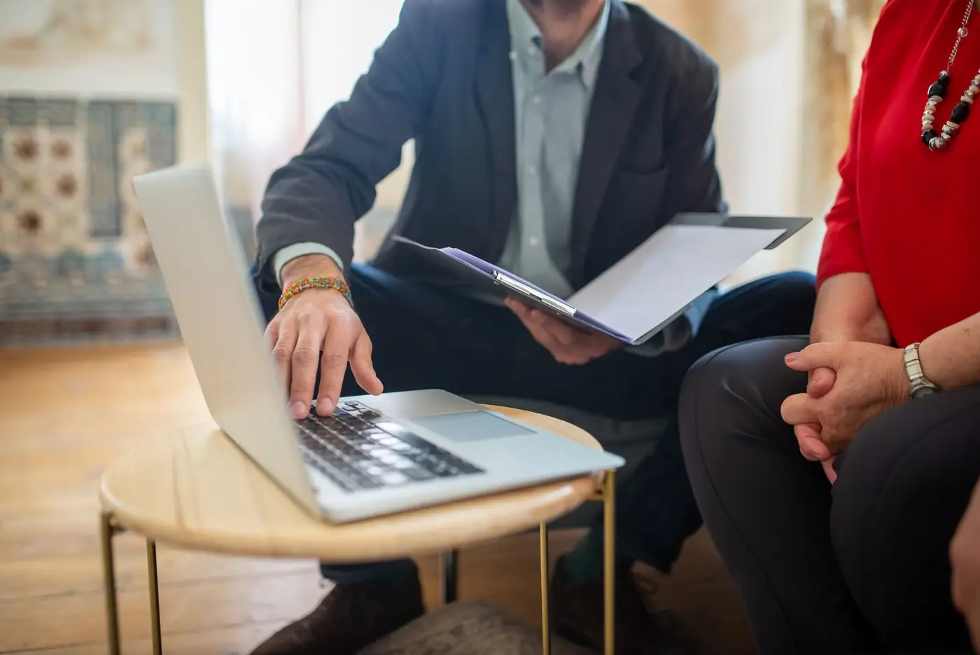 Adviser working through paperwork on a laptop and clipboard with a client