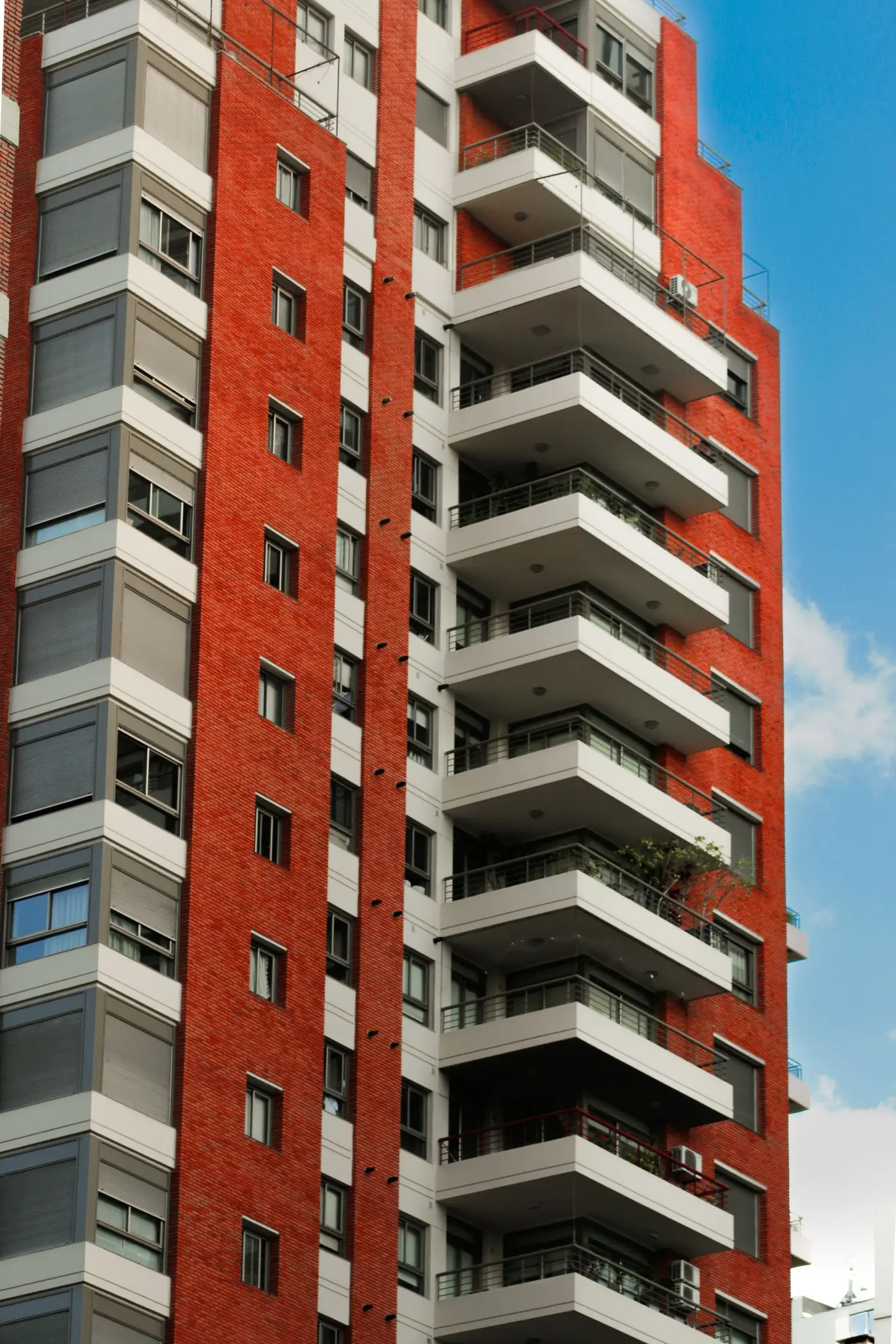 Balconies stacked up the corner of a red-brick apartment block